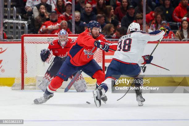 Joel Edmundson of the Washington Capitals defends against Boone Jenner of the Columbus Blue Jackets during a game at Capital One Arena on November...