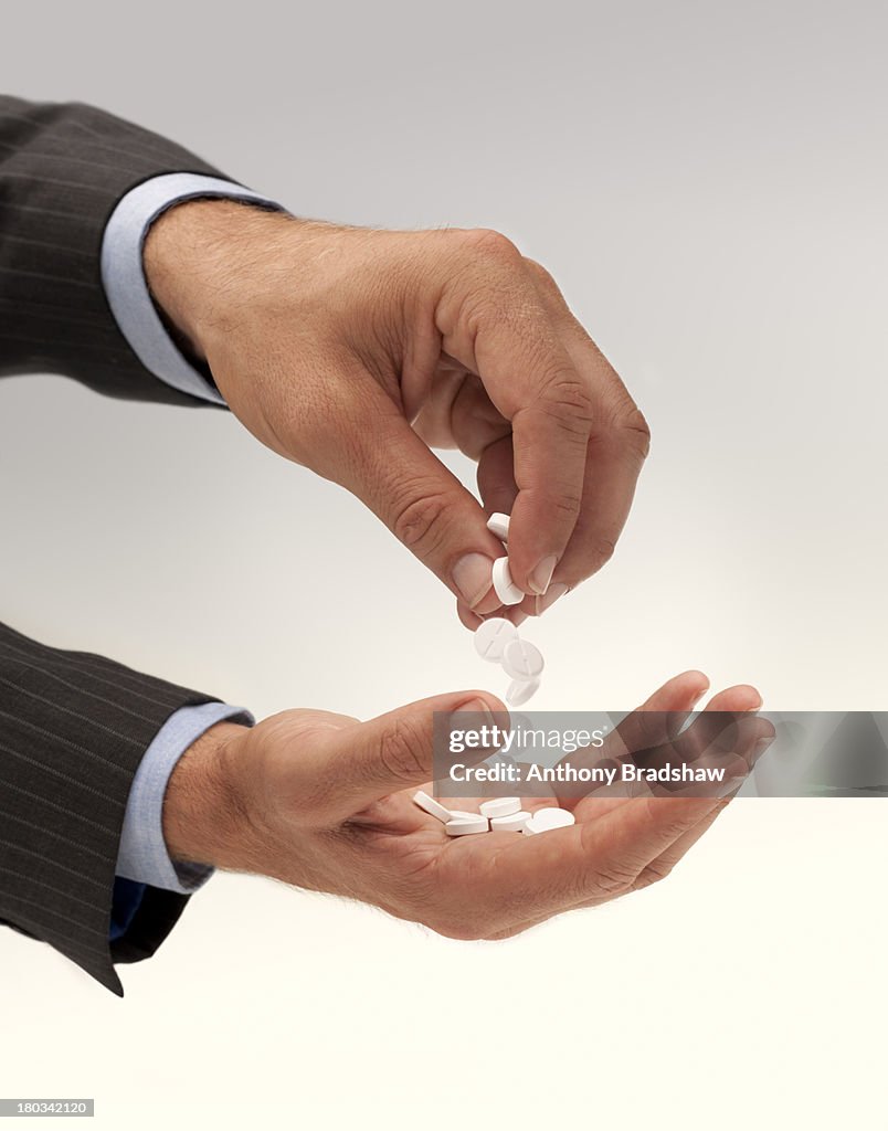Pills being passed from one hand and another