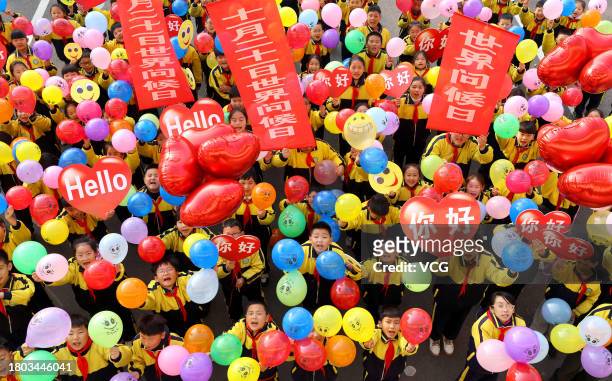 Students show greeting cards and colorful balloons ahead of World Hello Day at a primary school on November 20, 2023 in Zaozhuang, Shandong Province...