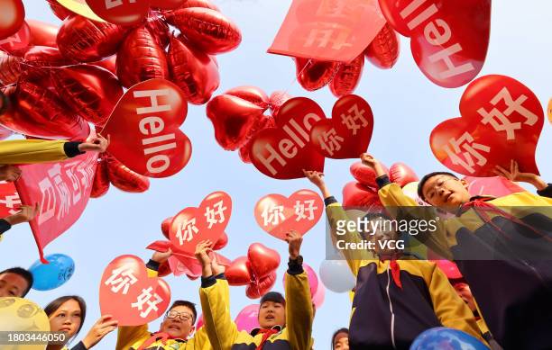 Students show greeting cards and colorful balloons ahead of World Hello Day at a primary school on November 20, 2023 in Zaozhuang, Shandong Province...