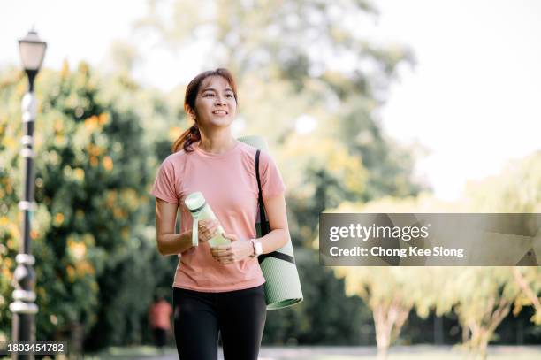 mujeres chinas asiáticas en un paseo matutino sosteniendo colchonetas de yoga. - pretty yoga mats fotografías e imágenes de stock
