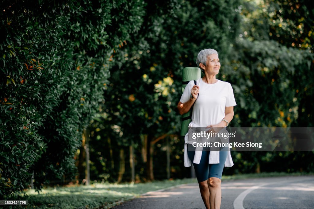 Asian Chinese Women on a morning walk holding yoga mats.