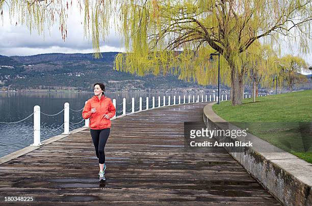 fit women running beside lake after rain - kelowna stock pictures, royalty-free photos & images
