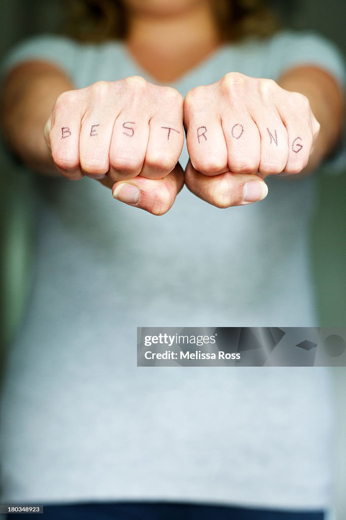 The words "BE STRONG" printed on two fists