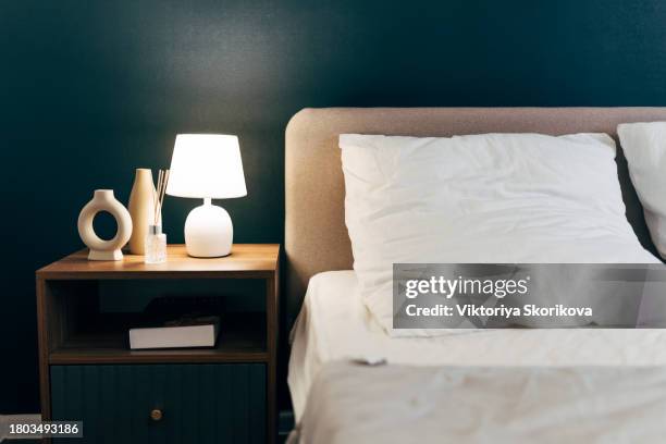 stylish golden lamp and stationery on a wooden bedside table in the bedroom. - headboard ストックフォトと画像
