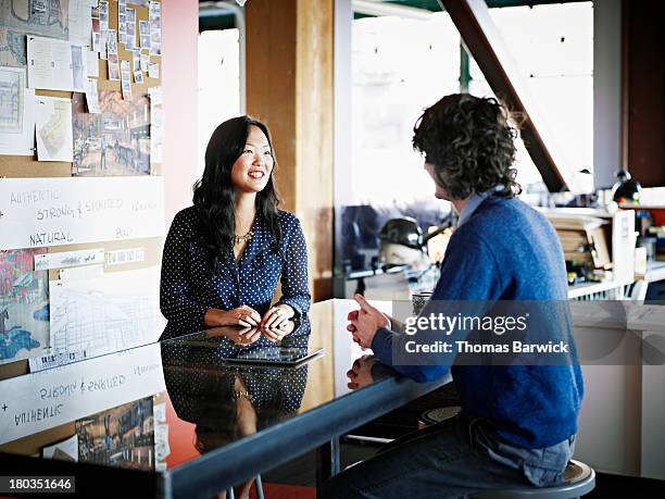 coworkers in discussion at table in office - 2013newwomen stock pictures, royalty-free photos & images