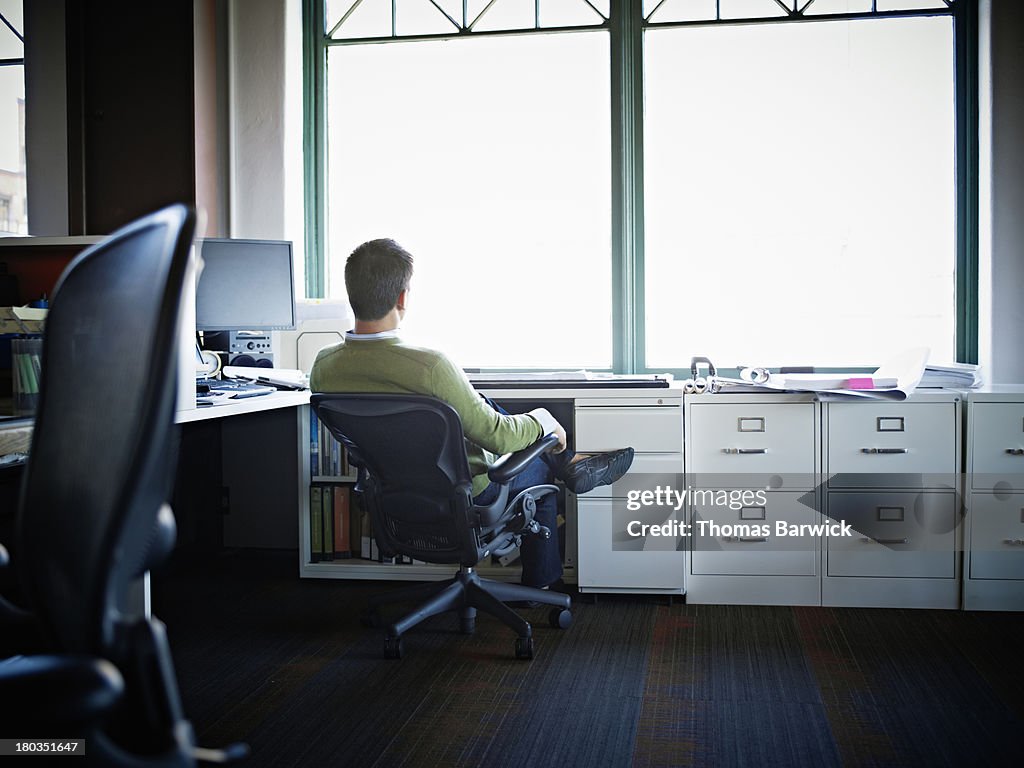 Businessman sitting in chair at desk rear view