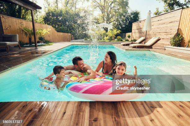 cheerful family having fun during summer day in the pool. - family pool stock pictures, royalty-free photos & images