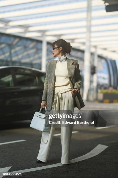 Heart Evangelista wears sunglasses, a white shirt, a beige oversized blazer jacket with printed houndstooth patterns, a pastel pale yellow / cream...