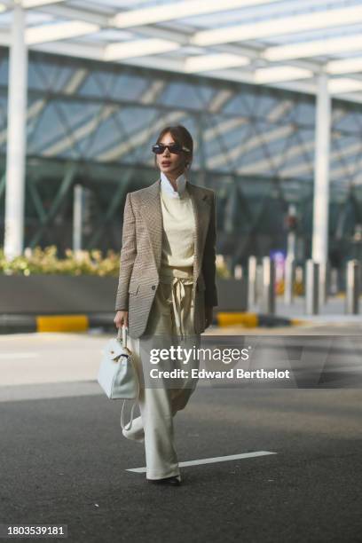 Heart Evangelista wears sunglasses, a white shirt, a beige oversized blazer jacket with printed houndstooth patterns, a pastel pale yellow / cream...