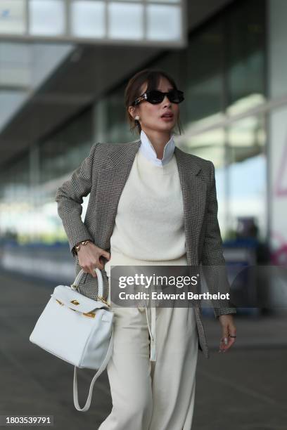 Heart Evangelista wears sunglasses, a white shirt, a beige oversized blazer jacket with printed houndstooth patterns, a pastel pale yellow / cream...