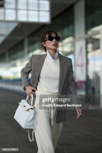 Heart Evangelista wears sunglasses, a white shirt, a beige oversized blazer jacket with printed houndstooth patterns, a pastel pale yellow / cream...