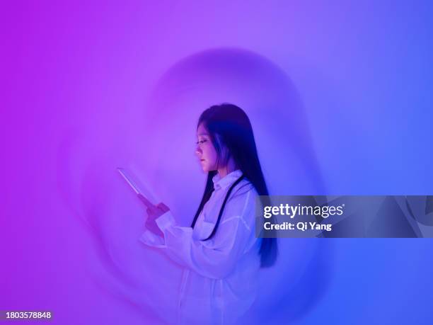 young asian woman using a digital tablet on neon color background - deep learning stock pictures, royalty-free photos & images