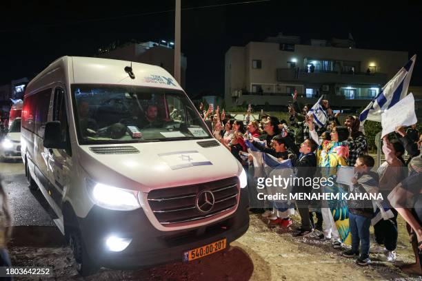 People cheer as a vehicle carrying hostages released by Hamas drives towards an army base in Ofakim, southern Israel, on November 26 after they were...