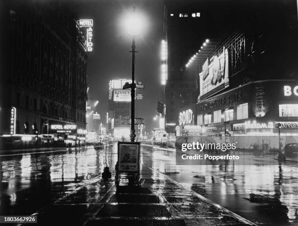 Night time view of traffic passing neon signs illuminating Times Square at the intersection of Broadway and 7th Avenue in midtown Manhattan, New York...