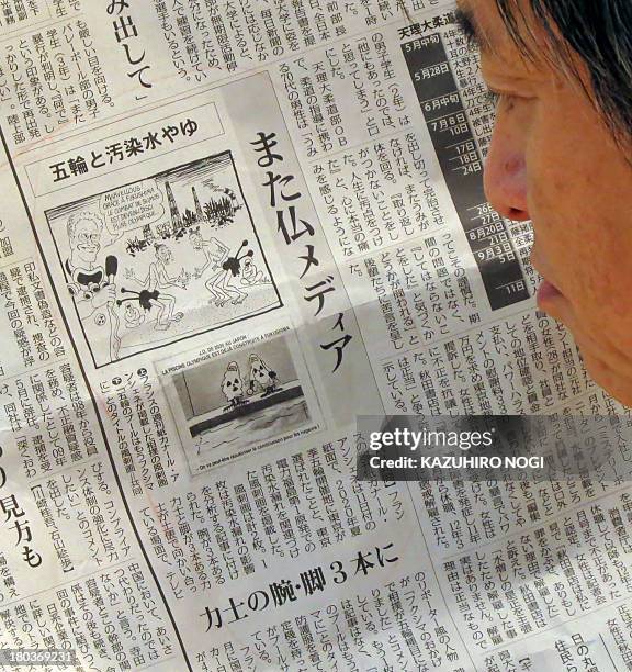 Man reads a Japanese local newspaper reporting cartoons published in a French newspaper, in Tokyo on September 12, 2013. Japan voiced anger September...