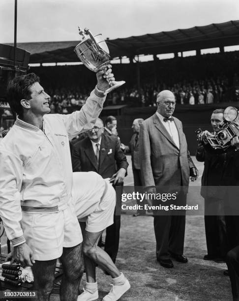 Australian tennis player Ashley Cooper holding up his trophy after winning the men's singles tournament at the Wimbledon Tennis Championships in...