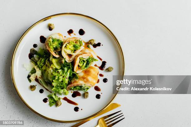 rolls of thin pancakes with smoked salmon, cream cheese and greens on plate on table. delicious and healthy breakfast or brunch. top view, copy space - maslenitsa stock pictures, royalty-free photos & images