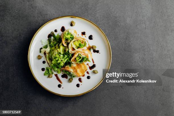 rolls of thin pancakes with smoked salmon, cream cheese and lettuce on plate on dark table. delicious and healthy breakfast or brunch. top view, copy space - maslenitsa stock pictures, royalty-free photos & images