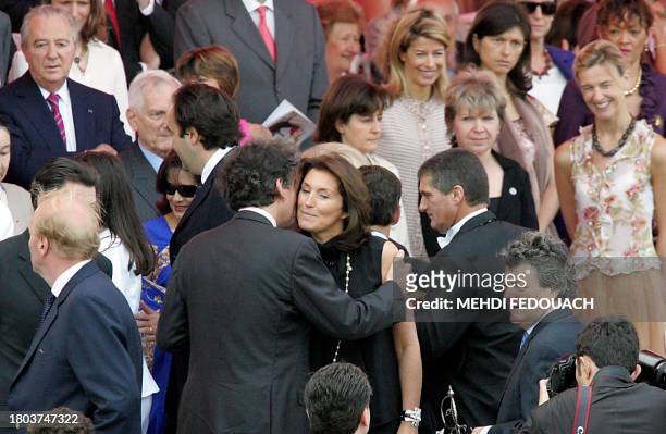 French Finance Minister Thierry Breton kisses Interior Minister Nicolas Sarkozy's wife Cecilia as they arrive for the annual Bastille day parade, 14...
