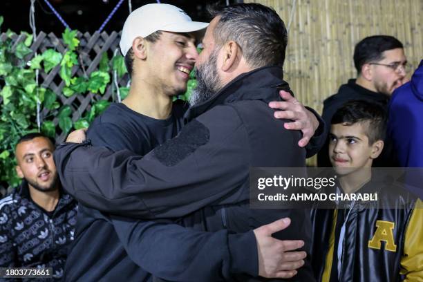 Palestinian Mohammed Al-Awar , former prisoner released from an Israeli jail in exchange for hostages freed by Hamas in Gaza, embraces his father...