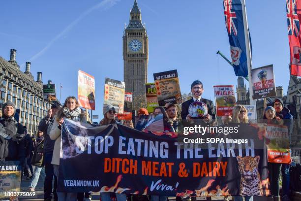 Protesters hold a "Stop eating the Earth, ditch meat and dairy" banner during the demonstration. Vegan activists staged a rally in Parliament Square...