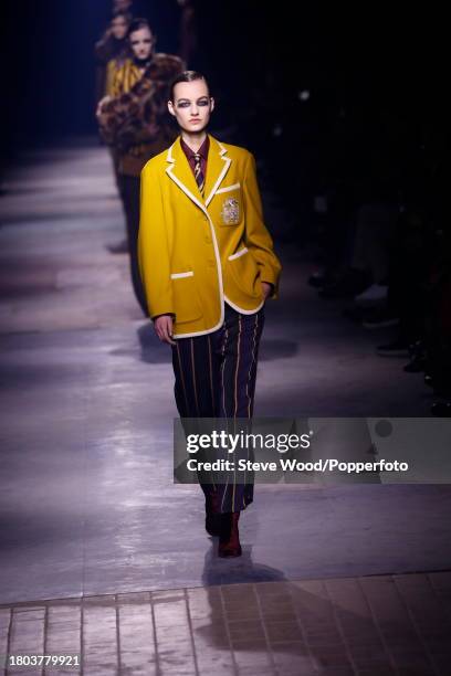 Model walks the runway at the Dries Van Noten show during Paris Fashion Week Autumn/Winter 2016/17, she wears a yellow varsity style blazer with wide...