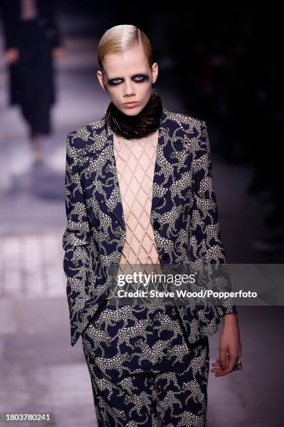 Model walks the runway at the Dries Van Noten show during Paris Fashion Week Autumn/Winter 2016/17, she wears a black trouser suit printed with white...