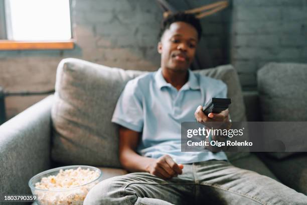 watching movies on tv at home. selective focus on african american hand with remote control - zapping stock pictures, royalty-free photos & images