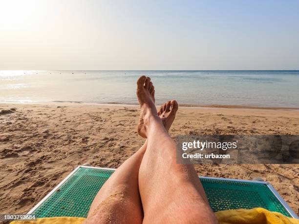 piedi del giovane mentre si rilassa sulla spiaggia in egitto - sedia a sdraio foto e immagini stock