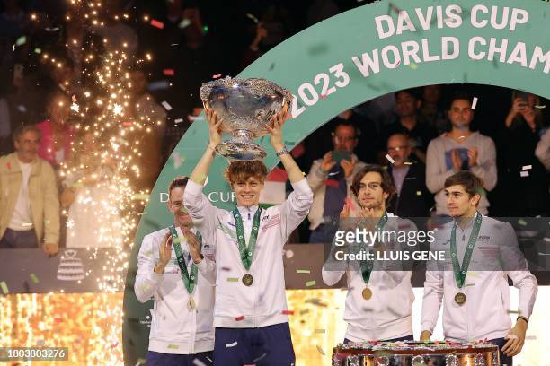 Italy's Jannik Sinner raises the trophy as he celebrates with teammates winning the Davis Cup tennis tournament after beating Australia at the Martin...