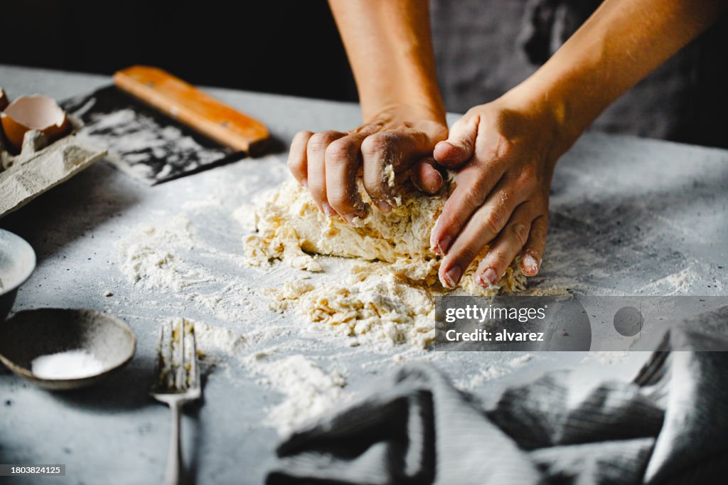 Close-up of hands kneading pasta dough on kitchen counter