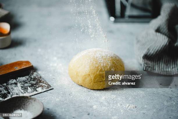 sprinkling flour on pasta dough over kitchen counter - sprinkling imagens e fotografias de stock