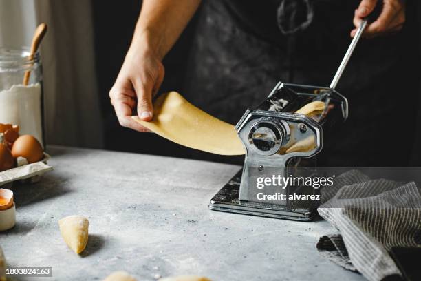 making homemade pasta with rolling machine on kitchen table - pasta machine stock pictures, royalty-free photos & images