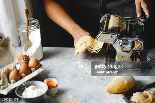 nahaufnahme einer frau, die zu hause mit einer maschine hausgemachte nudeln herstellt - artisan food stock-fotos und bilder