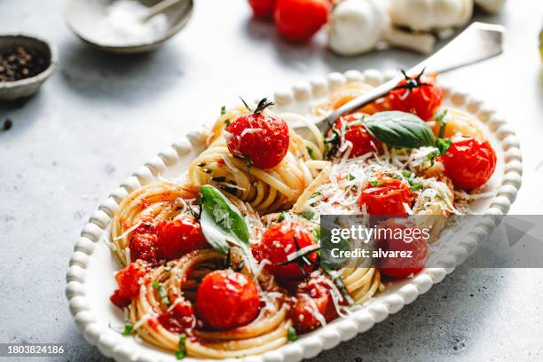 nahaufnahme von frisch zubereiteten tomaten-basilikum-nudeln, serviert auf einem teller - italienische küche stock-fotos und bilder