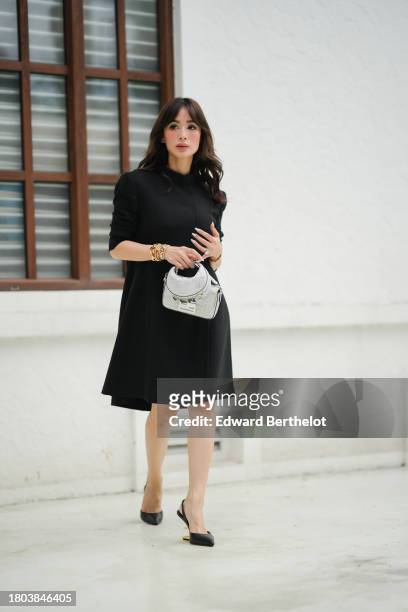 Heart Evangelista wears a Fendi full look, a black midi gathered dress with shoulder pads, Cartier golden jewelry / bracelets, gray and silver shiny...