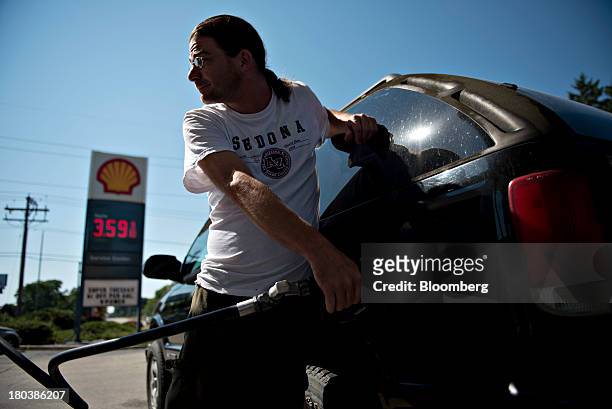 Customer puts fuel in his vehicle at a Shell gas station in Peoria, Illinois, U.S., on Wednesday, Sept. 11, 2013. Gasoline climbed in New York...