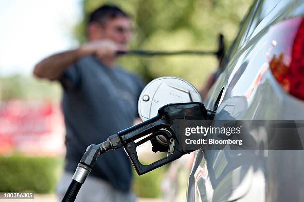 Charlie Gourd cleans his windshield while putting fuel in his vehicle at a Royal Dutch Shell Plc gas station in Peoria, Illinois, U.S., on Wednesday,...