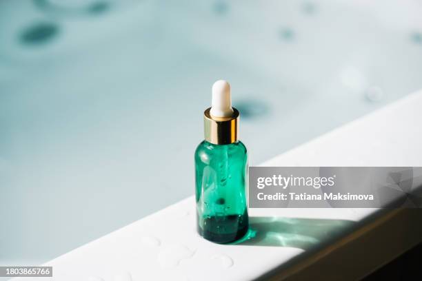 green bottle with face serum in bathroom. - toiletries stock pictures, royalty-free photos & images