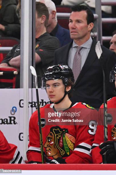 Connor Bedard of the Chicago Blackhawks and Head Coach Luke Richardson watch their team play in the second period against the St. Louis Blues on...