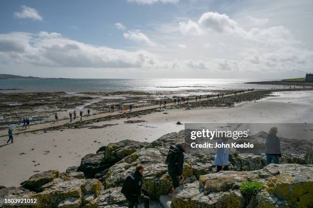 People walk out to St Michael's Mount, a tidal island in Mount's Bay on September 18, 2023 in Marazion, Cornwall, England.