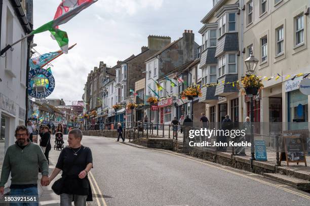 Couple hold hands as they walk past shops along the high street in Market Jew Street on September 18, 2023 in Penzance, Cornwall, England.