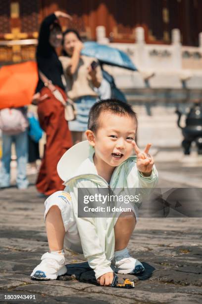 a happy boy posing for a portrait photo in front of the glazed tiles at the temple of heaven in beijing - fine arts center stock pictures, royalty-free photos & images