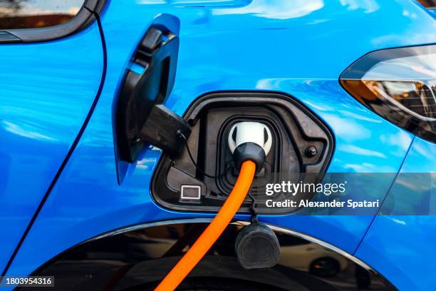 electric car charging on the street, car plug in the charger close-up - electric car charger imagens e fotografias de stock