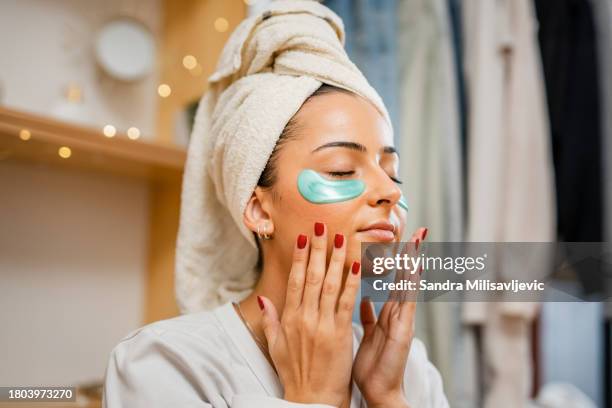one woman with towel on her head sitting on the floor at home doing self-care activities - gezichtsmasker stockfoto's en -beelden