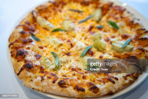 close up of a round deep crust pizza with tomato and mozzarella already sliced - napoli pizza stock pictures, royalty-free photos & images