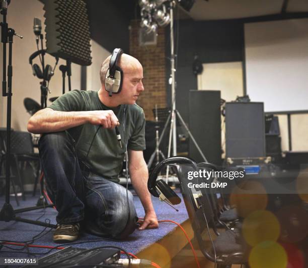 audio technician, headphones and man with cable at stage to test system, equipment or installation. sound engineer at theatre with wire for music production, performance or rehearsal event at concert - stereo installation stock pictures, royalty-free photos & images