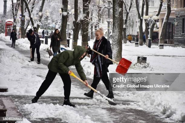People shovel snow on a sidewalk on November 20, 2023 in Poltava, Ukraine. Since the snowfall that began on November 19 in Poltava Oblast, there have...