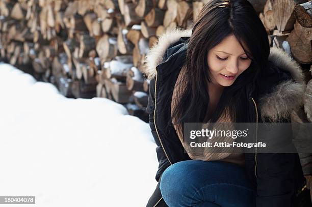 candid portrait of young female in front of log pile - traditional parka stock pictures, royalty-free photos & images